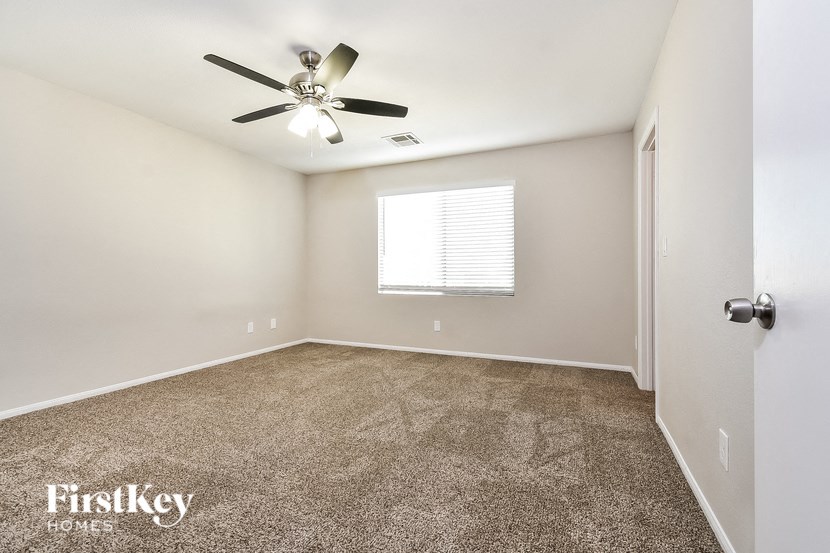 the master bedroom has carpeted floors and a ceiling fan