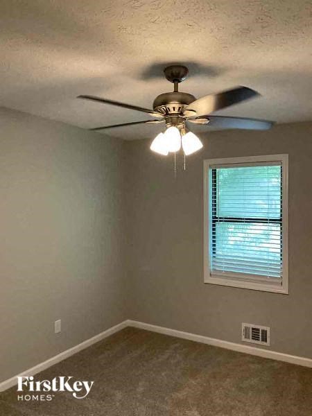 A room with a ceiling fan and a window with blinds.