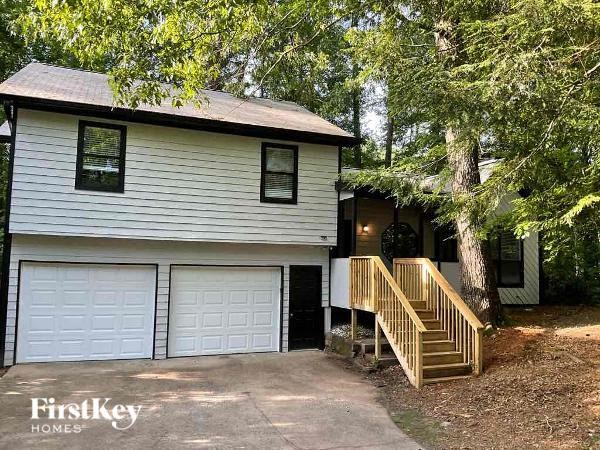 A house with a garage and a porch is surrounded by trees.