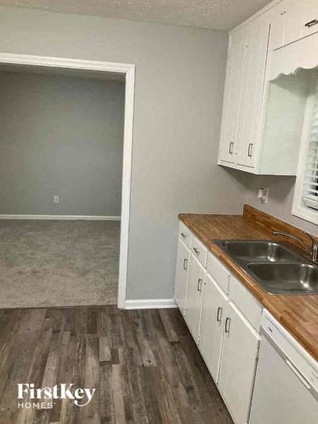 A kitchen with white cabinets and a wooden counter top.