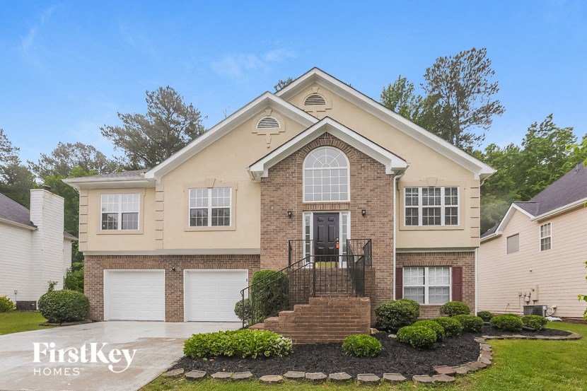 a beige brick house with white garage doors