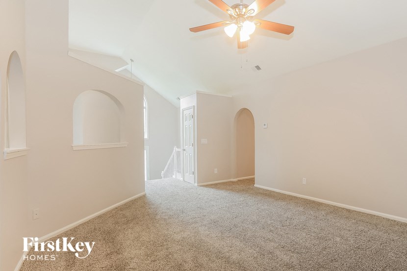 a spacious living room with carpet and a ceiling fan