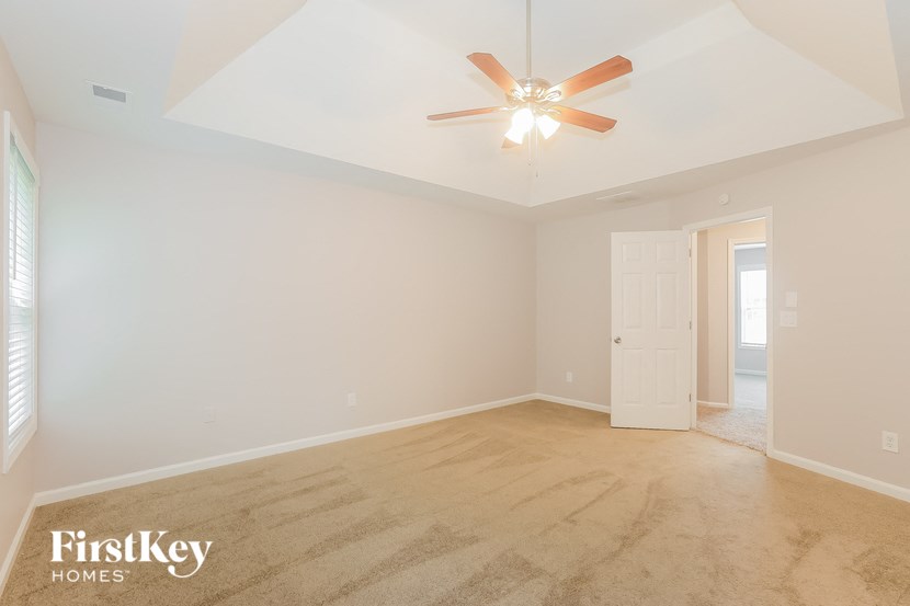 an empty living room with a ceiling fan and a white door