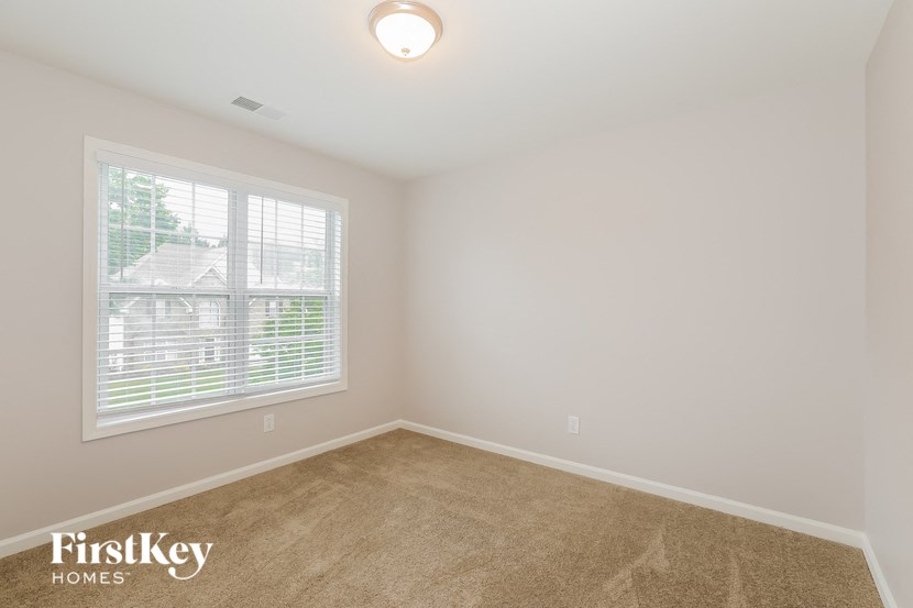 an empty room with a large window and carpet