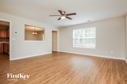A spacious room with wooden flooring and a ceiling fan.