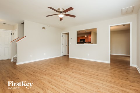 A spacious room with a ceiling fan and wooden flooring.
