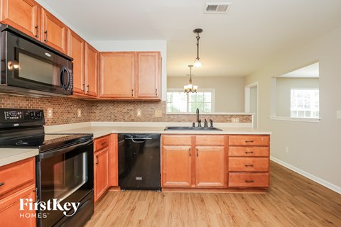 A kitchen with wooden cabinets and a black dishwasher.