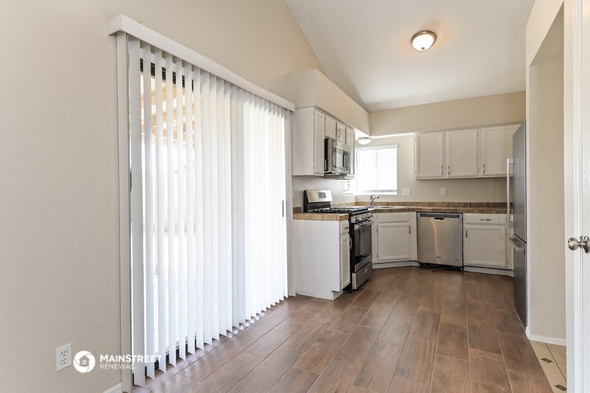 a kitchen with white cabinets and a window with white blinds
