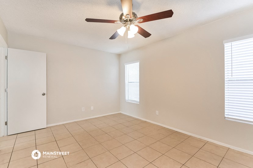 a living room with a ceiling fan and a tiled floor