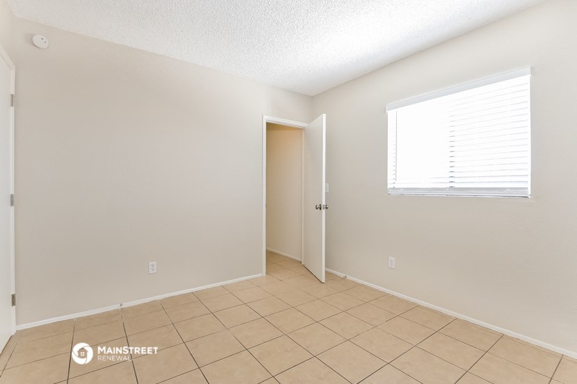 a spacious living room with a tiled floor and a door to a closet