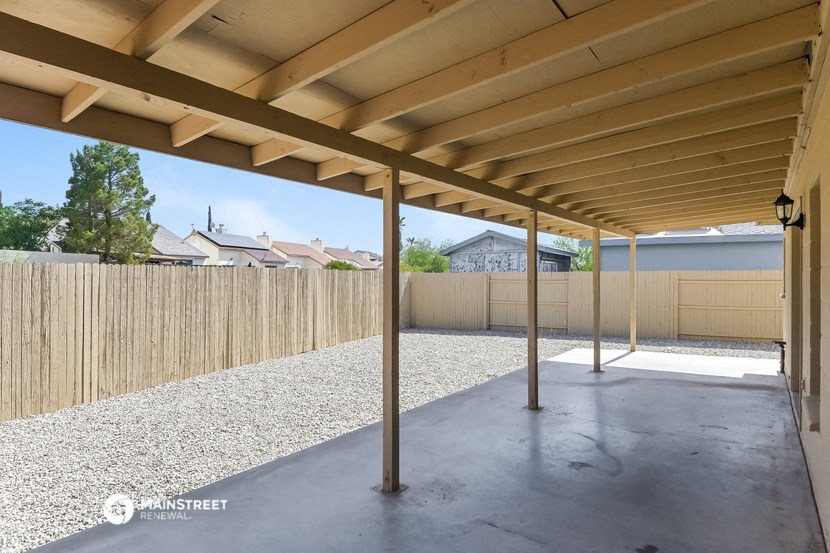 a patio with a wooden fence and awning in a yard