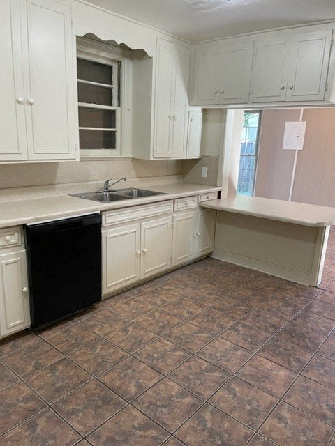 A kitchen with white cabinets and a black dishwasher.