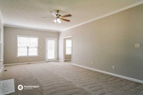 the spacious living room with ceiling fan and carpet