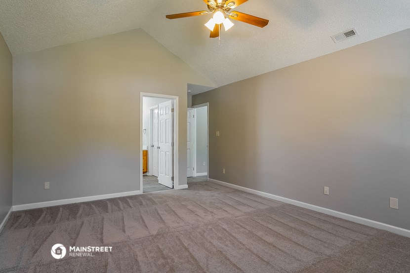 the living room and dining room of an empty house with a ceiling fan