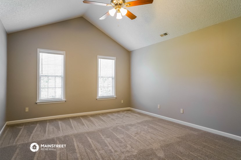 the spacious living room with carpeting and a ceiling fan