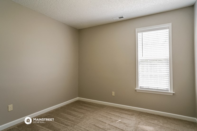 a bedroom with a window and a wooden floor