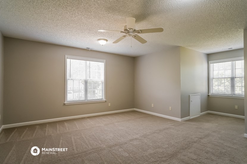 the spacious living room with ceiling fan and window
