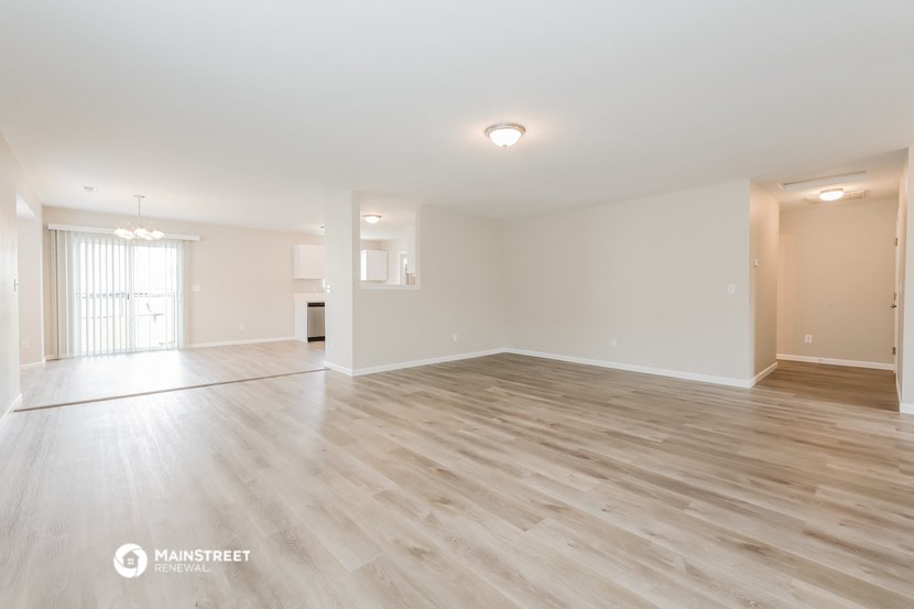 the spacious living room with wood flooring and white walls