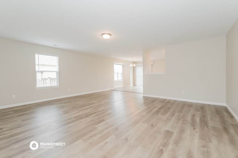 the living room and dining room of an apartment with wood flooring