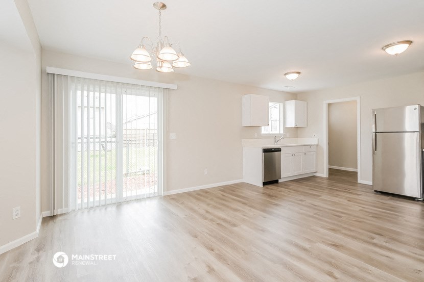 the living room and kitchen of an apartment with a large sliding glass door