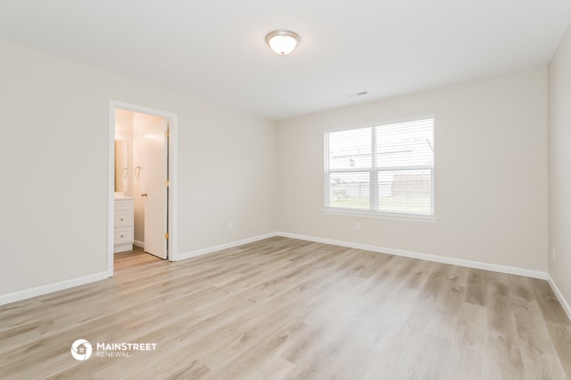 the spacious living room with wood flooring and a large window