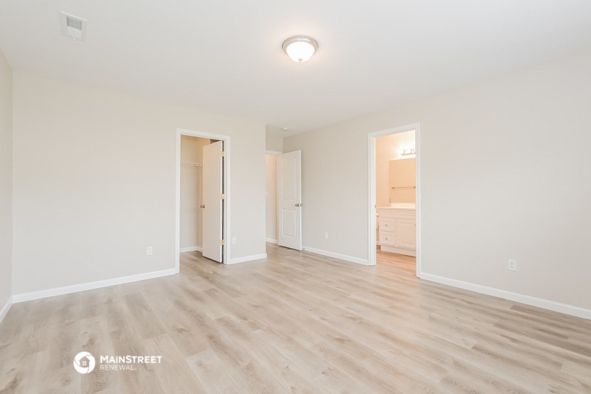 the spacious living room with wood flooring and white walls