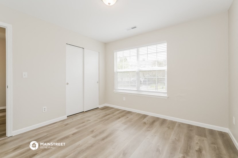 the spacious living room with wood flooring and a large window