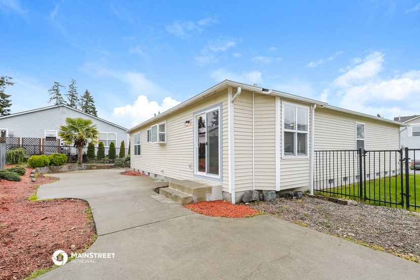 a white house with a driveway and a black fence