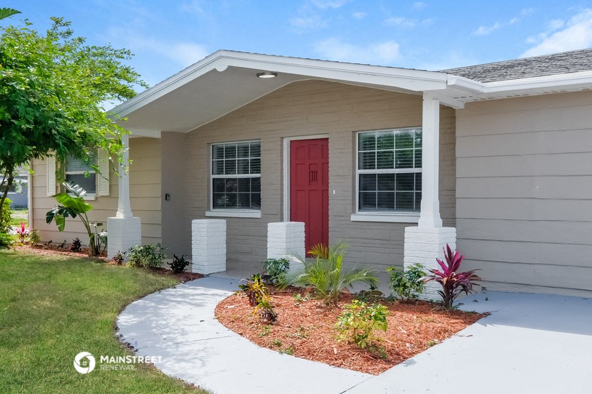 a home with a red door and a sidewalk in front of it