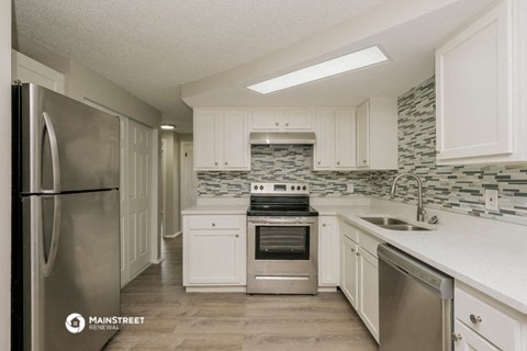 a kitchen with white cabinets and stainless steel appliances
