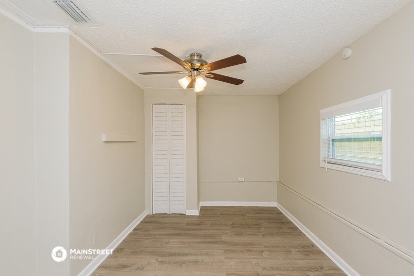 an empty room with a ceiling fan and a window