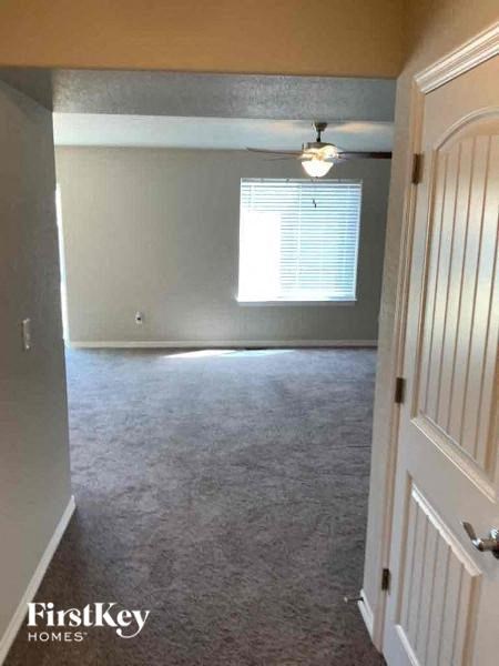 an empty living room with a ceiling fan and a window