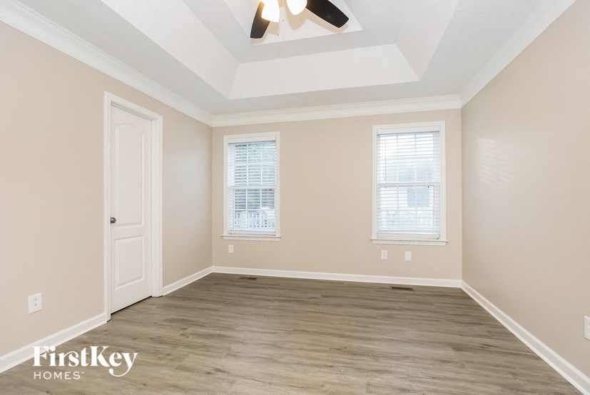 an empty room with a ceiling fan and two windows