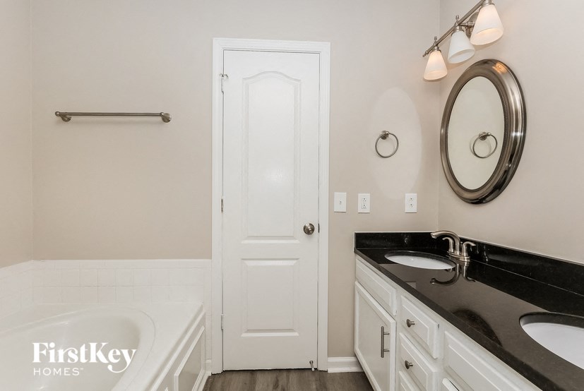 a bathroom with a sink and a tub and a white door