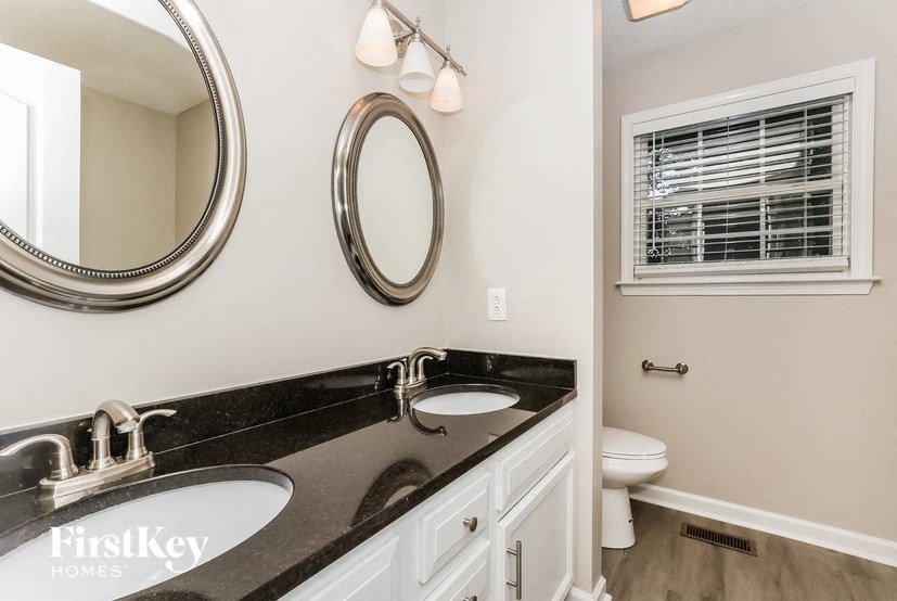 a bathroom with two sinks and a toilet and a mirror