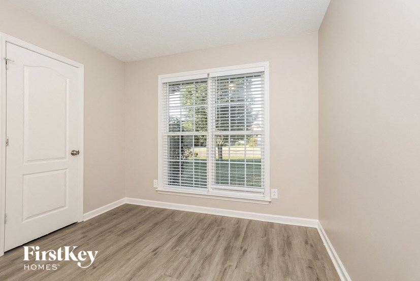 a bedroom with a large window and wooden floors