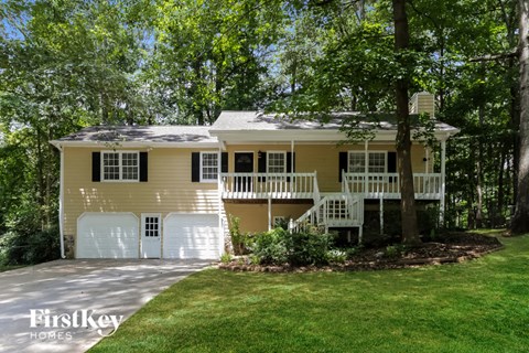 a yellow house with a white garage door and a porch