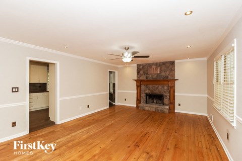a living room with a fireplace and wooden floors and a ceiling fan