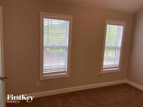 a living room with two windows and a carpet
