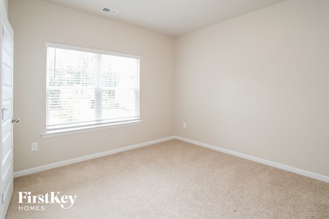 a bedroom with a large window and beige carpet