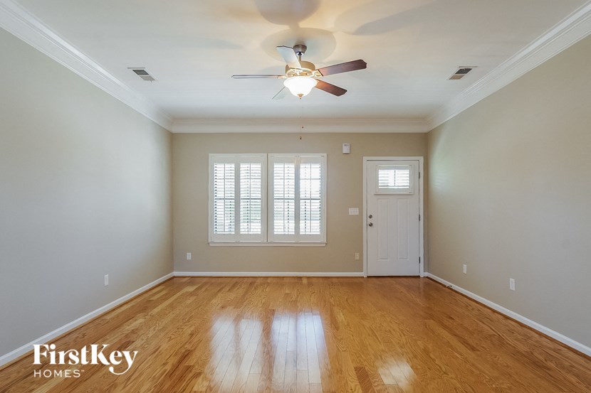 an empty living room with a ceiling fan and a door
