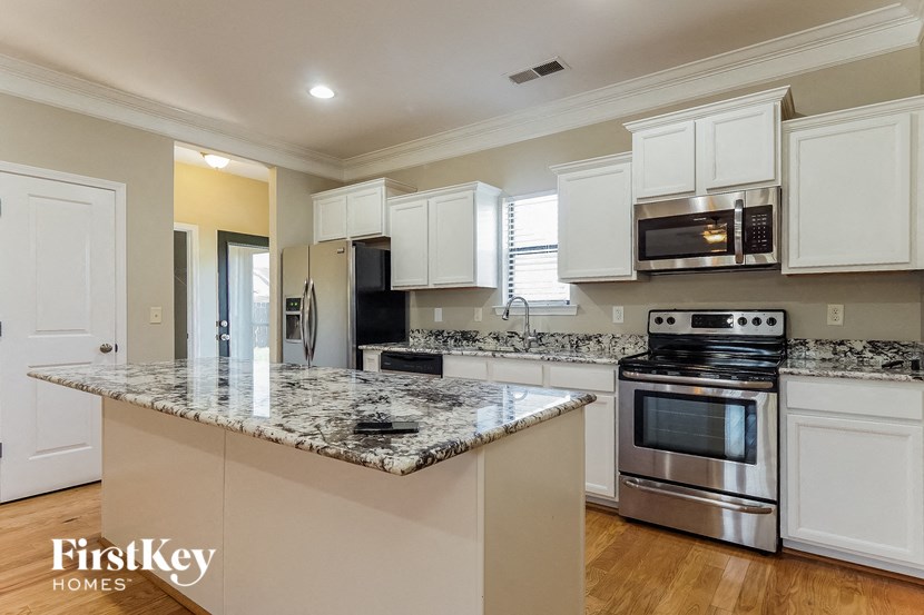a kitchen with white cabinets and a marble counter top