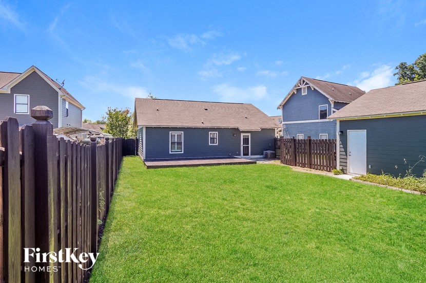 the backyard of a blue house with a yard and a fence