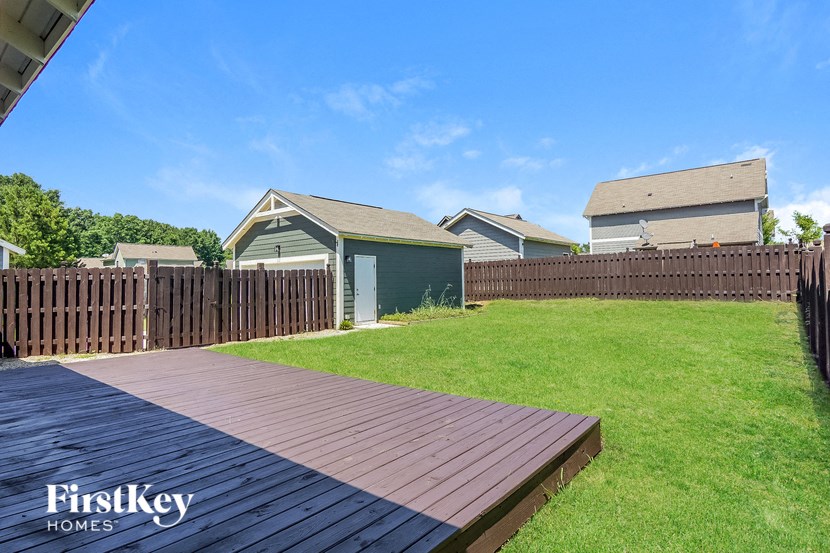 a backyard with a wooden deck and a fence