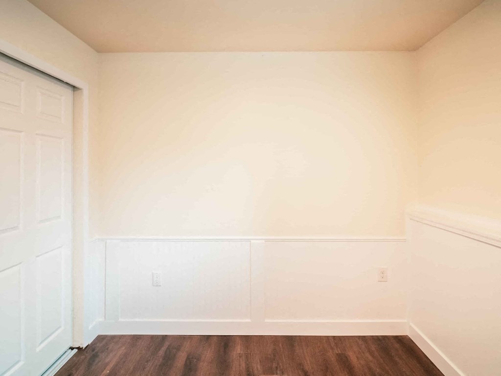a room with white walls and a wooden floor and a door