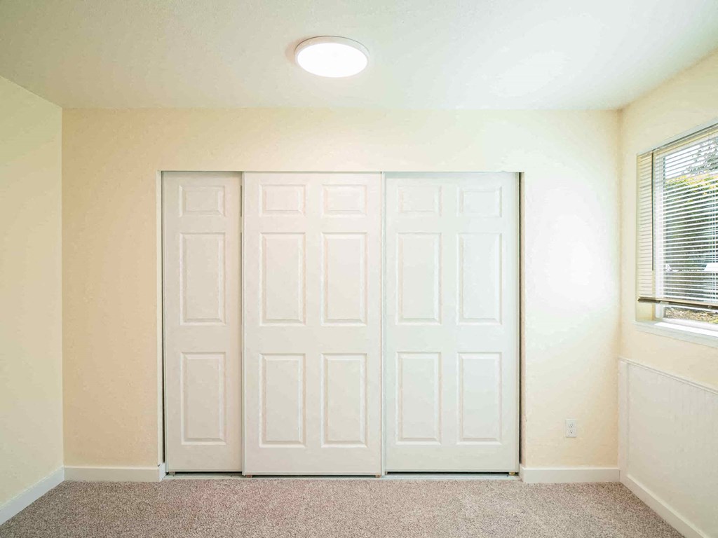 an empty room with white doors and a window