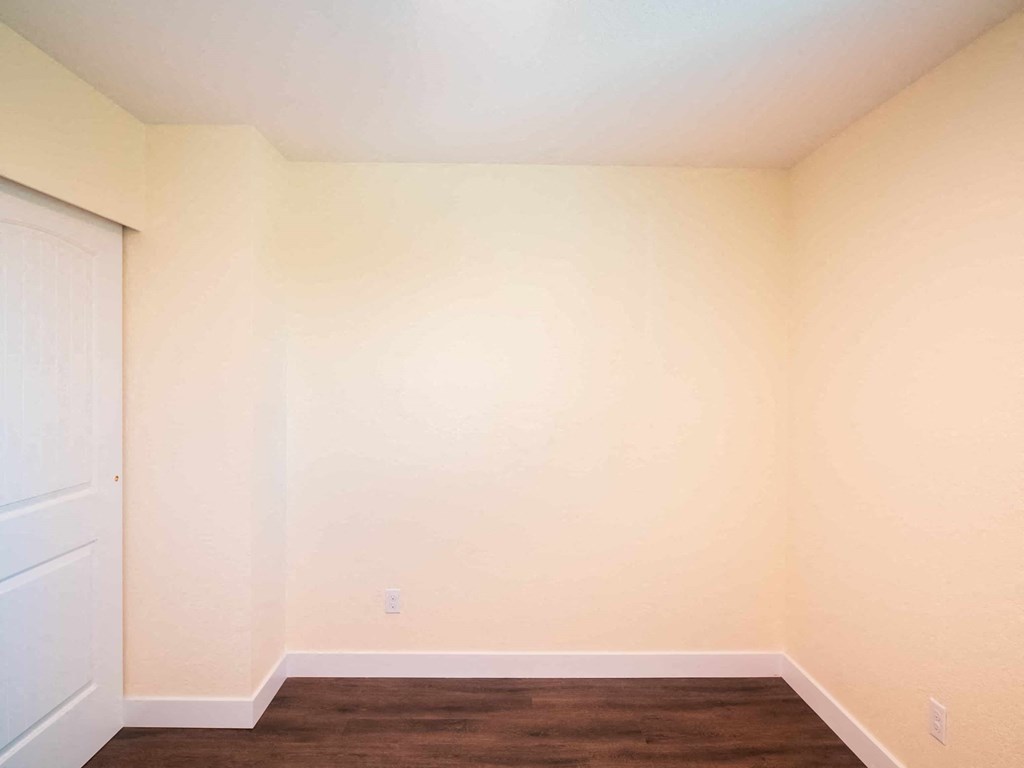 a room with white walls and a wooden floor and a white door