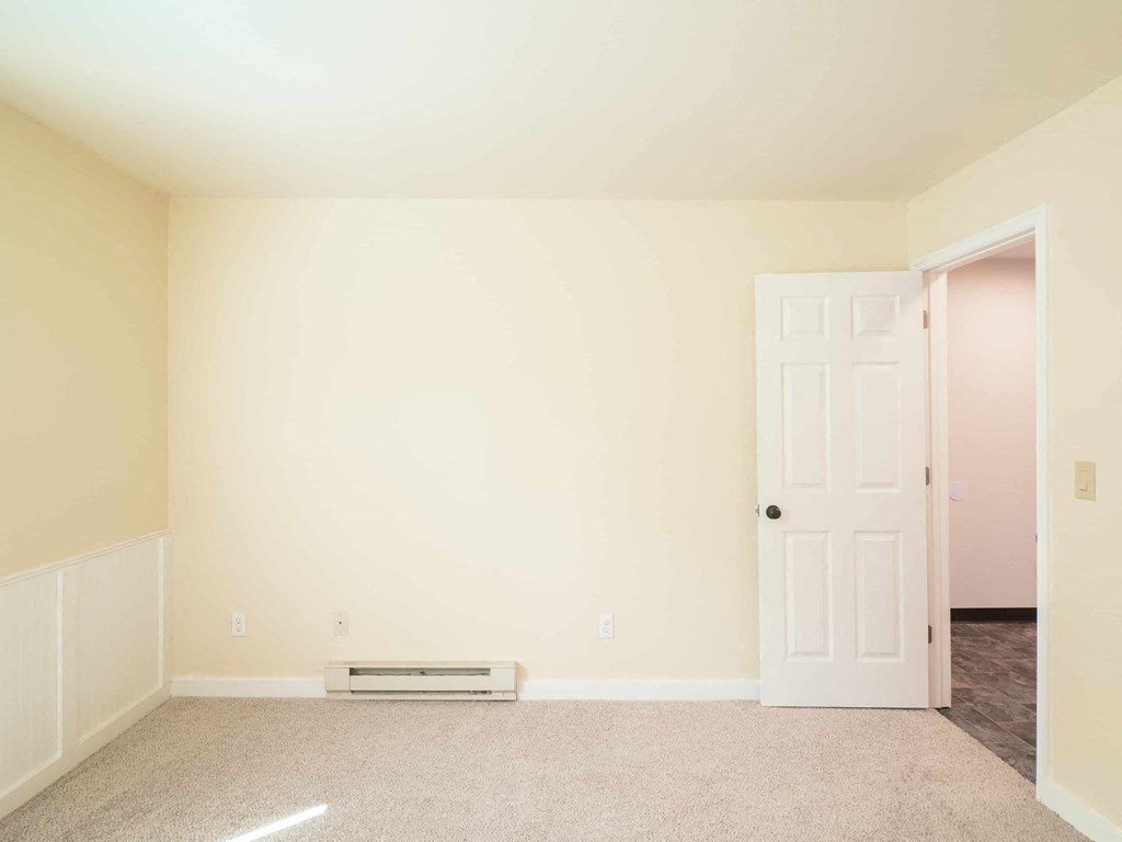 an empty room with a door and a heater on the floor