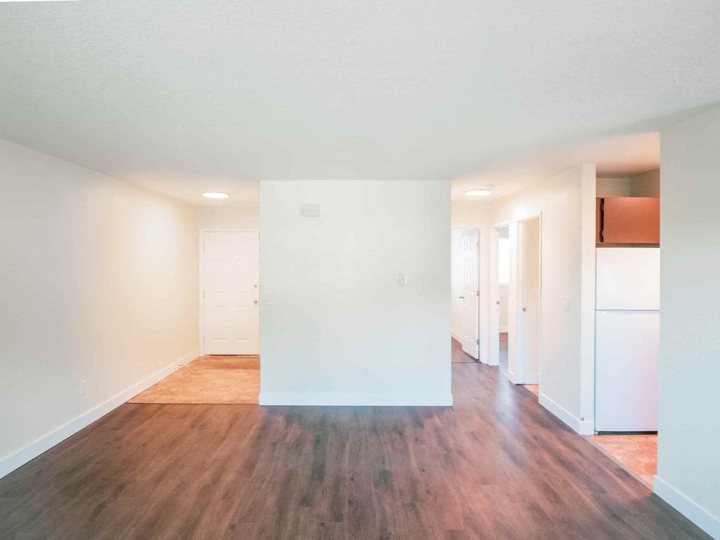an empty living room with white walls and wood floors
