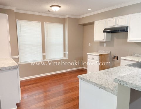 a kitchen with white cabinets and a hard wood floor
